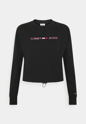 T-shirt court à manches longues noir avec "TOMMY JEANS" et un logo rouge, blanc et bleu brodé sur la poitrine.