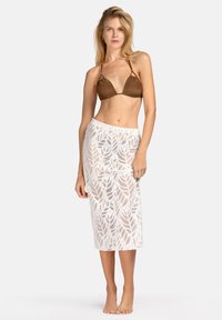 Brązowy trójkątny biustonosz kąpielowy z cienkimi ramiączkami, w zestawie z białą spódnicą do kolan z liściastym wzorem i przezroczystą teksturą.