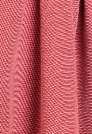 Gestructureerde stof in een roze tint, met een diamantpatroon en een grove weving, die zacht valt om zijn gestructureerde ontwerp te onthullen.