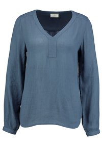 Blouse bleue à manches longues en tissu texturé, présentant un col en V et une patte sans boutons, avec des poignets retroussés et un ourlet légèrement arrondi.