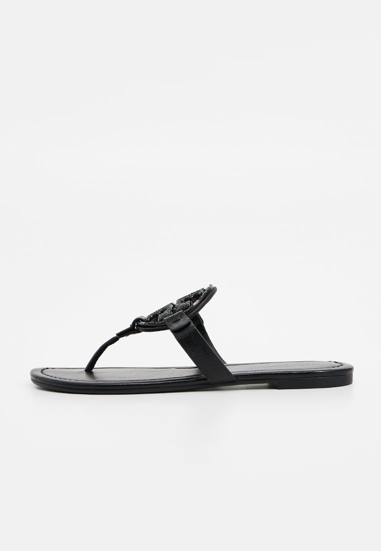 Schwarze flache Sandalen mit einem Zehentrenner-Design, ausgestattet mit einem strukturierten Riemen und einer glatten, rechteckigen Sohle. Schlichter und minimalistischer Stil.