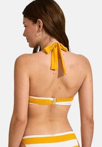 Bandeau de bikini rayé jaune et blanc avec un design à nouer à l'arrière et un détail de fermoir métallique. Le matériau semble texturé.