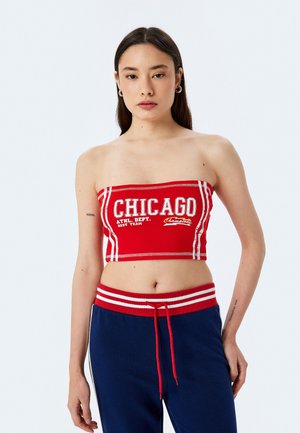 Top court sans bretelles rouge avec des accents blancs et du texte "CHICAGO". Le tissu est ajusté et présente des coutures contrastantes.