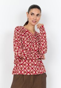 Langärmlige Bluse mit einem roten, cremefarbenen und grünen wirbelnden Blattmuster, aus weichem Stoff, mit V-Ausschnitt und Knopfdetail entlang der Vorderseite.