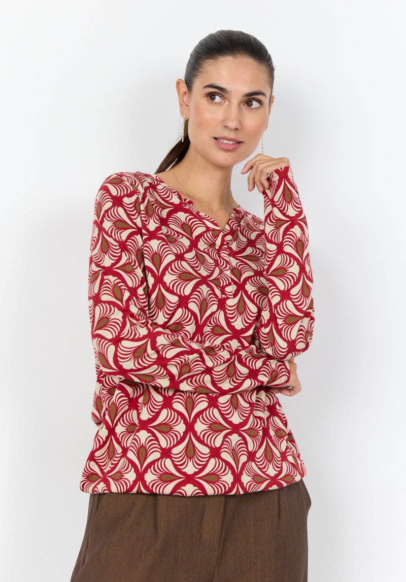 Langärmlige Bluse mit einem roten, cremefarbenen und grünen wirbelnden Blattmuster, aus weichem Stoff, mit V-Ausschnitt und Knopfdetail entlang der Vorderseite.