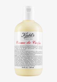 Kiehl's Crème de Corps, 250 ml, genomskinlig flaska med ett vitt pump-lock, har en etikett med svart och röd text som detaljerar ingredienser och instruktioner.