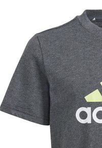 Czarny bawełniany t-shirt z okrągłym dekoltem, krótkimi rękawami oraz dużym białym i jasnobrązowym logo na przodzie.