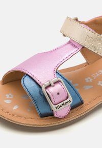 Sandale multicolore pour enfants avec une tige métallique rose et bleue, une sangle beige, une boucle argentée et une semelle intérieure à motifs floraux.