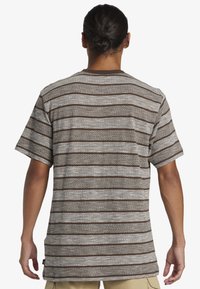 Bruin en crème gestreepte t-shirt met korte mouwen, een textuurpatroon, ronde halslijn en een relaxed fit, met een klein logo label aan de zijkant.