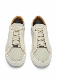 Sneaker in rete beige con accenti in suede, punta rotonda e superficie testurizzata. Presenta lacci beige e un'etichetta con logo sul lato. Suola in gomma.