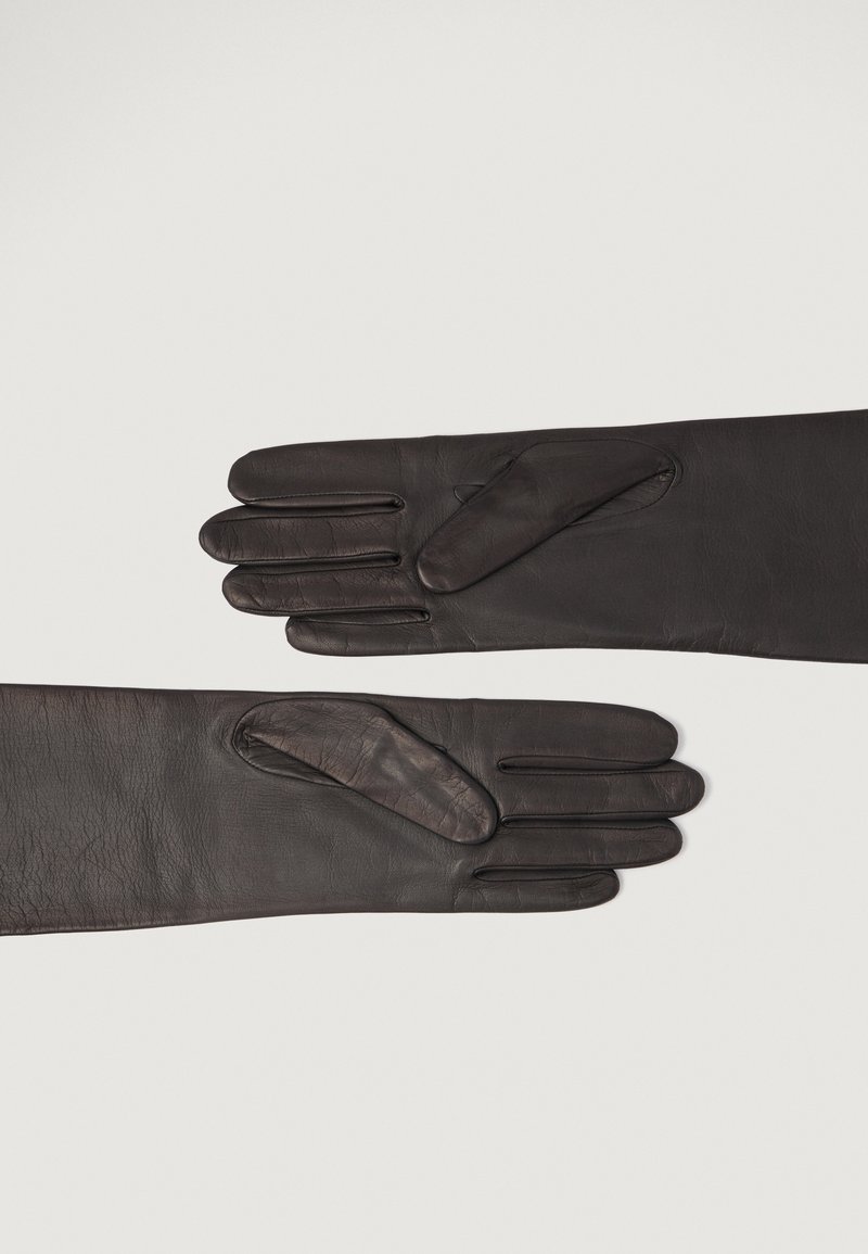 Lange sorte læderhandsker liggende flade med fingrene strakt, der viser tekstur og stikninger på en neutral baggrund.