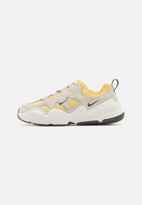 Lys grå og gul sneaker med teksturert mesh- og semsket skinnoverdel, tykk hvit mellomsole, svart gummisåle og snøring.