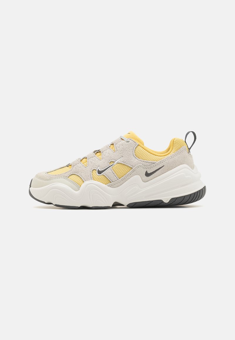Lys grå og gul sneaker med teksturert mesh- og semsket skinnoverdel, tykk hvit mellomsole, svart gummisåle og snøring.