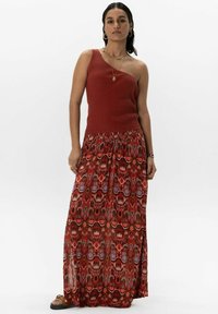 Robe maxi avec un corsage à côtes, une seule épaule, de couleur brun rougeâtre ; la jupe fluide présente un motif géométrique multicolore vibrant.
