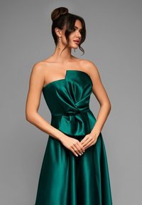 Abito in satin verde smeraldo con design senza spalline, caratterizzato da un corpetto attorcigliato e una gonna fluente. Texture liscia e silhouette elegante.