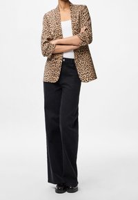 Marynarka w beżowe i czarne cętki w stylu lamparta; ma luźny krój i podwinięte rękawy. Połączona z czarnymi dżinsami o szerokich nogawkach i wysokim stanie.