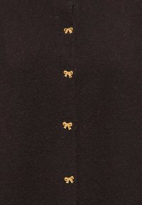 Schwarze Strickjacke mit sechs goldfarbenen Schleifen als Knöpfen, strukturiertem Stoff und klassischem Knopfverschluss.