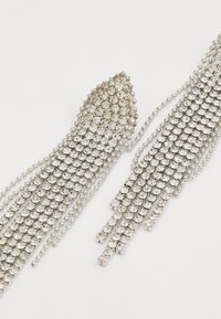 Cercei cu tol pentru bătături din cristal argintiu, având un model în grilă, cu un vârf ascuțit și șiruri de mărgele ce se scurg pentru un textura detaliată și strălucire.