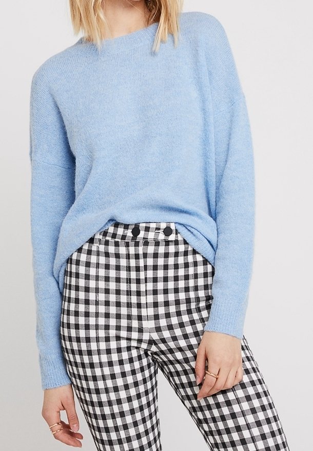 Pull doux bleu clair à coupe décontractée. Associé à un pantalon taille haute à carreaux vichy noir et blanc, orné de deux boutons.