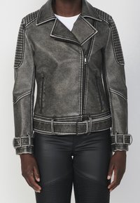 Giacca biker in ecopelle grigia con colletto strutturato, dettagli trapuntati sulle spalle, zip in argento e vita con cintura.
