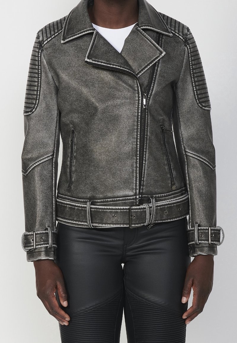 Giacca biker in ecopelle grigia con colletto strutturato, dettagli trapuntati sulle spalle, zip in argento e vita con cintura.