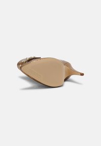 Beige stiletto-sandal med tekstureret syntetisk overdel, dekorative perler og spids tå. Har en ribbet gummisål for godt greb.