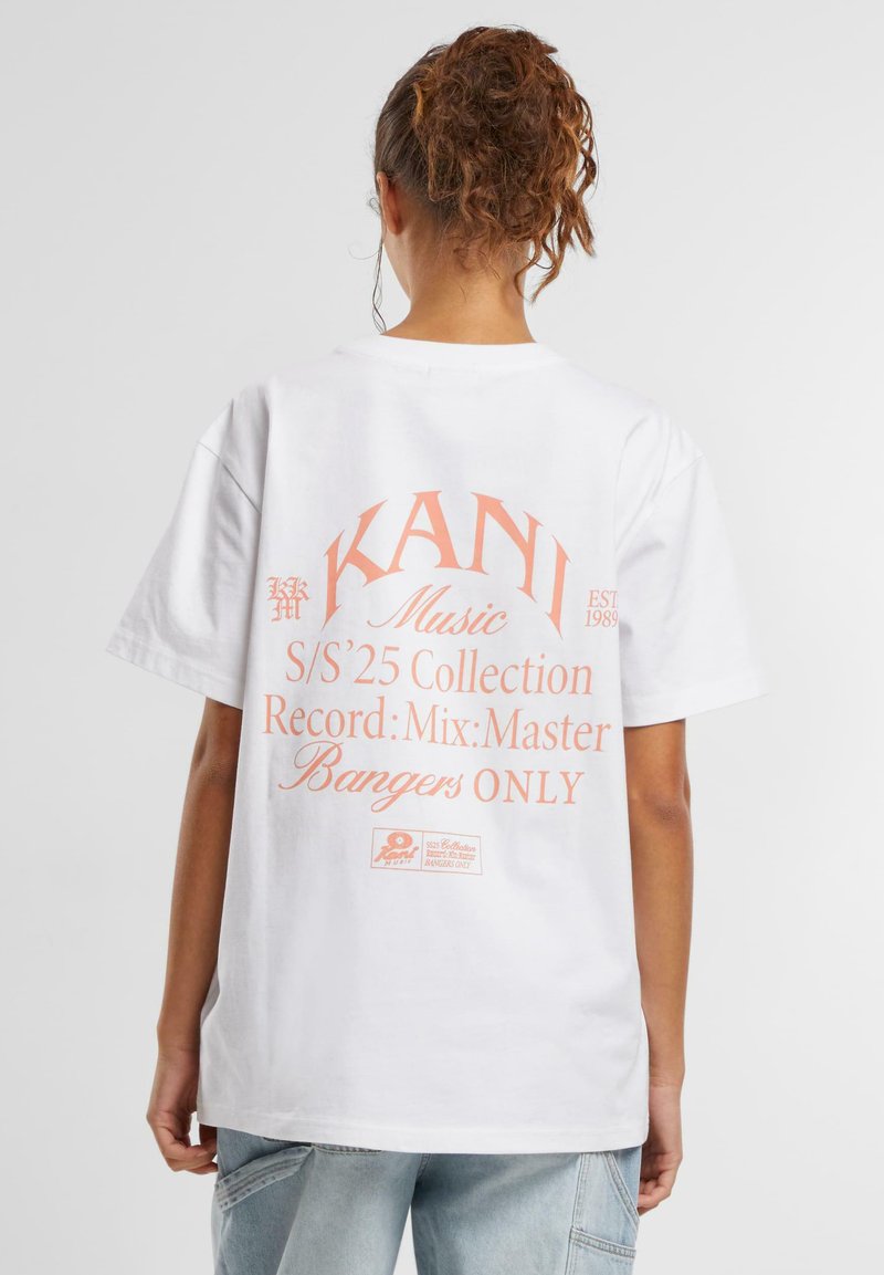 Bílý bavlněný tričko s růžovým grafickým textem na zádech, uvádějícím "KANI Music," "S/S'25 Collection," a "Bangers ONLY."