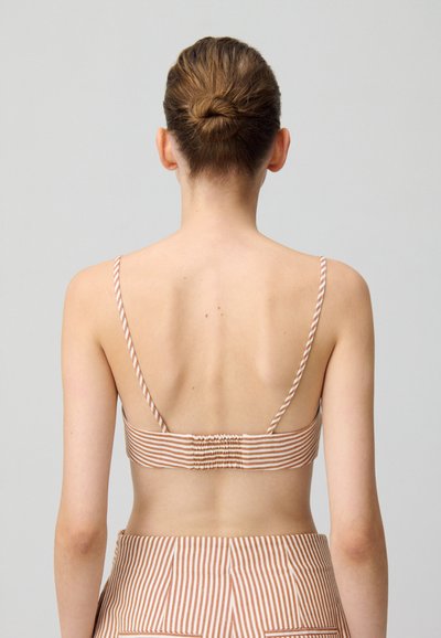Bralette a rayas en tela suave, con finas correas ajustables, respaldo elástico y un diseño ajustado en tonos cálidos de durazno y beige.