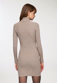 Abito a maglia a coste di colore taupe chiaro, con maniche lunghe e scollatura alta. La vestibilità slim mette in risalto la silhouette.