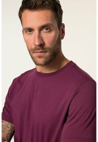 Maronfarvet crew neck t-shirt lavet af blødt stof. Den har korte ærmer og en afslappet pasform, med diskret logodetalje nær kanten.