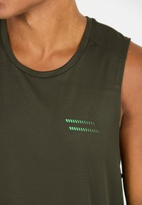Olijfgroen mouwloos sporttopje van textiel met een gestructureerde stof en een reflecterende groene streepdesign op de linkerborst.