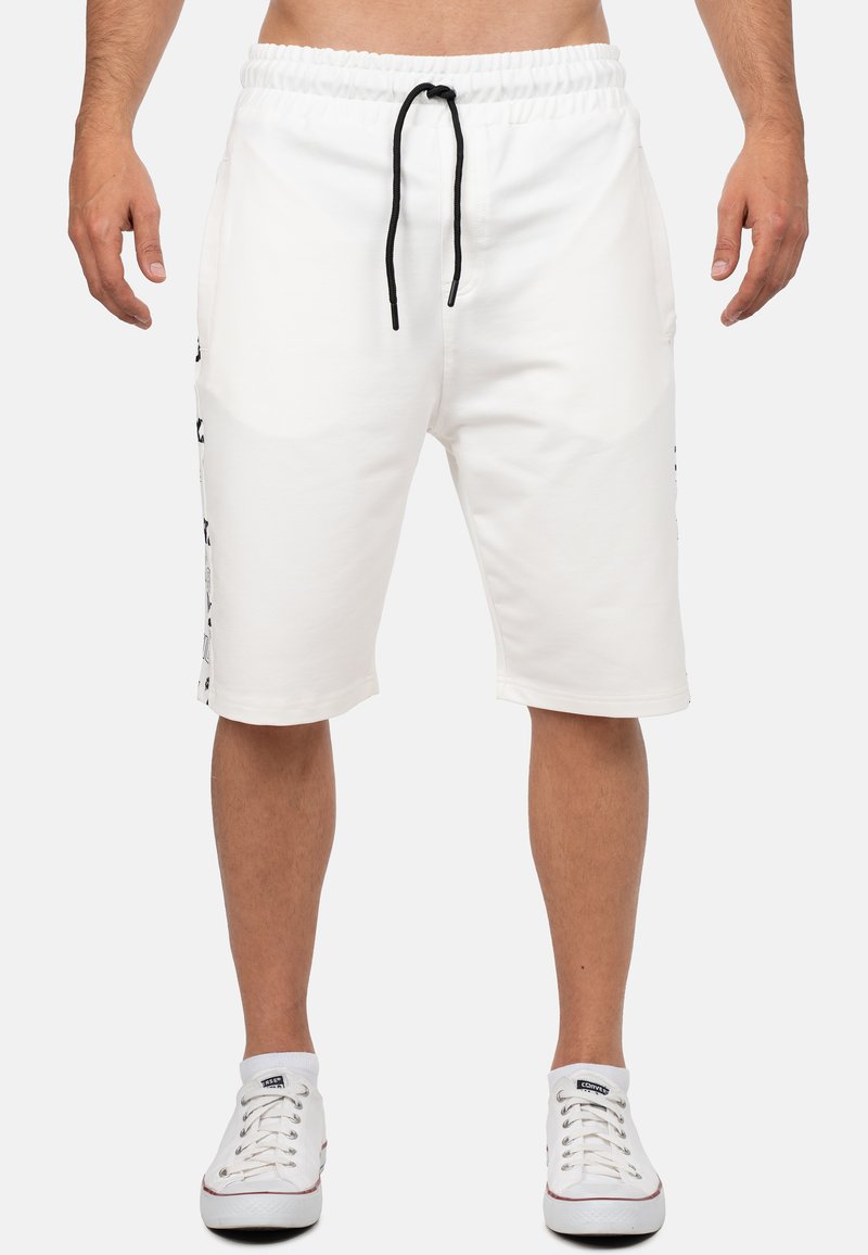 Weiße Baumwollshorts mit elastischem Bund und Kordelzug, ausgestattet mit Seitentaschen und schwarzen Akzenten am Saum und an den Seiten.
