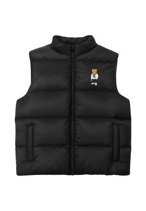 Veste sans manches matelassée noire avec fermeture éclair à l'avant et petit ours brodé portant une chemise blanche et un pull bleu sur la poitrine.