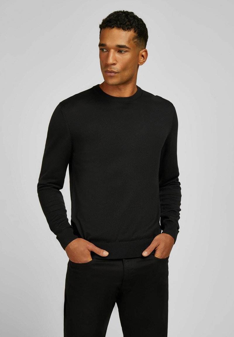 Zwarte gebreide trui met een ronde hals, lange mouwen en ribgebreide manchetten. Gladde textuur, aansluitend ontwerp en minimalistische stijl.