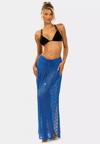 Niebieska, koronkowa spódnica maxi z przewiewnym, ażurowym wzorem, posiadająca elastyczny pas ze sznurkiem i rozcięciami z boków, zestawiona z czarnym bikini.