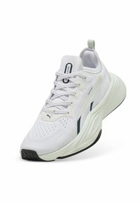 Scarpa atletica bianca con tomaia in rete texturizzata, dettagli verdi, suola spessa e battistrada in gomma nera a contrasto, dotata di lacci e marchio.