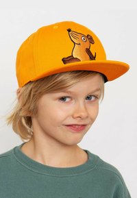 Gelbe Kappe aus Stoff mit strukturiertem Design. Auf der Vorderseite befindet sich eine gestickte braune Hundillustration.