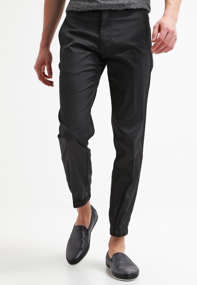 Pantalones negros de corte ajustado, hechos de un material ligero y suave. Cuentan con una cintura elástica y tobillos ajustados. Aptos para uso informal.