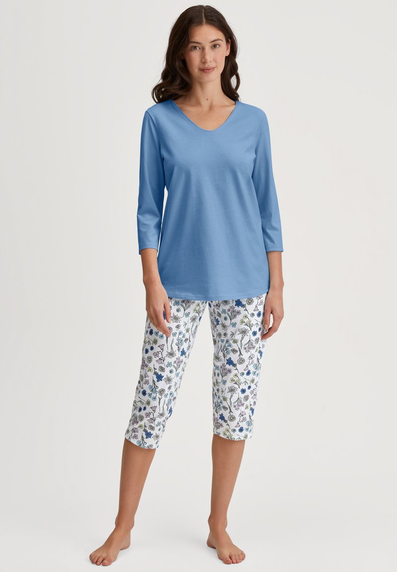 Lichtblauw, driekwart mouw V-hals top gecombineerd met bloemenprint capri broek met verschillende kleuren op een witte achtergrond.