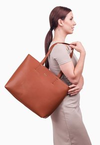 Hnědá kožená taška přes rameno s dvěma popruhy, obdélníkový tvar, hladká textura, se subtilním logem a minimalistickými designovými detaily.