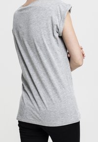 T-shirt grigia a maniche corte realizzata in tessuto morbido, con una vestibilità rilassata e scollo rotondo; la vista dal retro mostra una texture liscia e linee pulite.