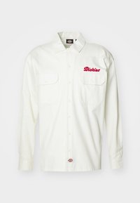 White long-sleeve shirt with two front pockets, embroidered red "Dickies" logo, button-up design, and durable cotton material.