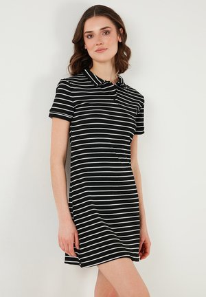 Rochie polo cu dungi alb-negru, cu guler și mâneci scurte, având o siluetă ajustată și o textură ribbed.