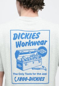 Γκρι βαμβακερό μπλουζάκι με μπλε γραφικό τύπωμα ενός κουτιού εργαλείων γεμάτου εργαλεία, με κείμενο που γράφει "DICKIES Workwear" και "The Only Tools for the Job!"