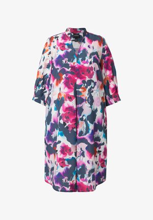 Knie-lange jurk met lange mouwen en een open kraag, met grote abstracte bloemmotieven in roze, paars, oranje, blauw en zwart op wit.