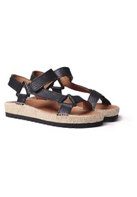 Black leather sandals with cross straps, woven espadrille sole, rubber outsole, and brown inner lining. Lightweight and casual design.