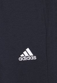 Sudadera azul marino con textura suave, que cuenta con un logo blanco de Adidas. Diseño sencillo, cuello redondo y puños acanalados.