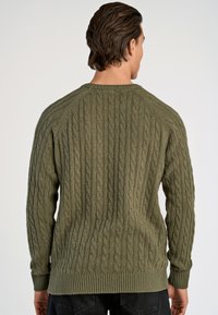 Olijfgroene gebreide trui met kabelpatronen, geribbelde manchetten en zoom. Heeft een ronde hals en raglanmouwen, met een gestructureerde stof.