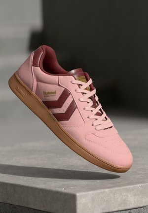 Hummel sneakers in light pink suede with maroon accents and logo, featuring a gum sole, round toe, and lace-up design.