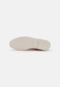 Suela de una zapatilla con una suela exterior de goma blanca texturizada. Forma redondeada y parte superior de color rosa claro con un acabado suave y detalles mínimos.